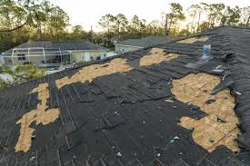 Residential roof with large section of shingles torn off exposing the decking