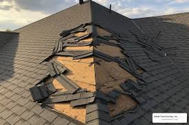 Close-up of a weathered asphalt shingle roof showing storm damage